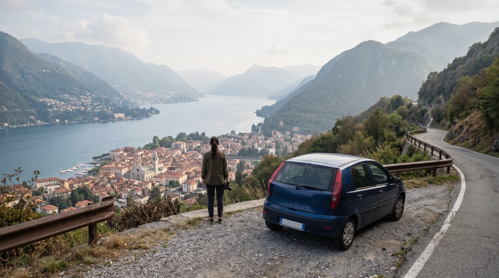 A small rental car parked on a hillside road above Como with the lake below, car rental in Como
