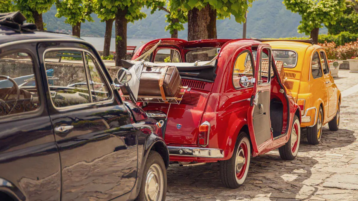 A vintage 1970 Fiat 500 parked by the Como lakefront on a Lake Como classic car rental tour in Como, Italy