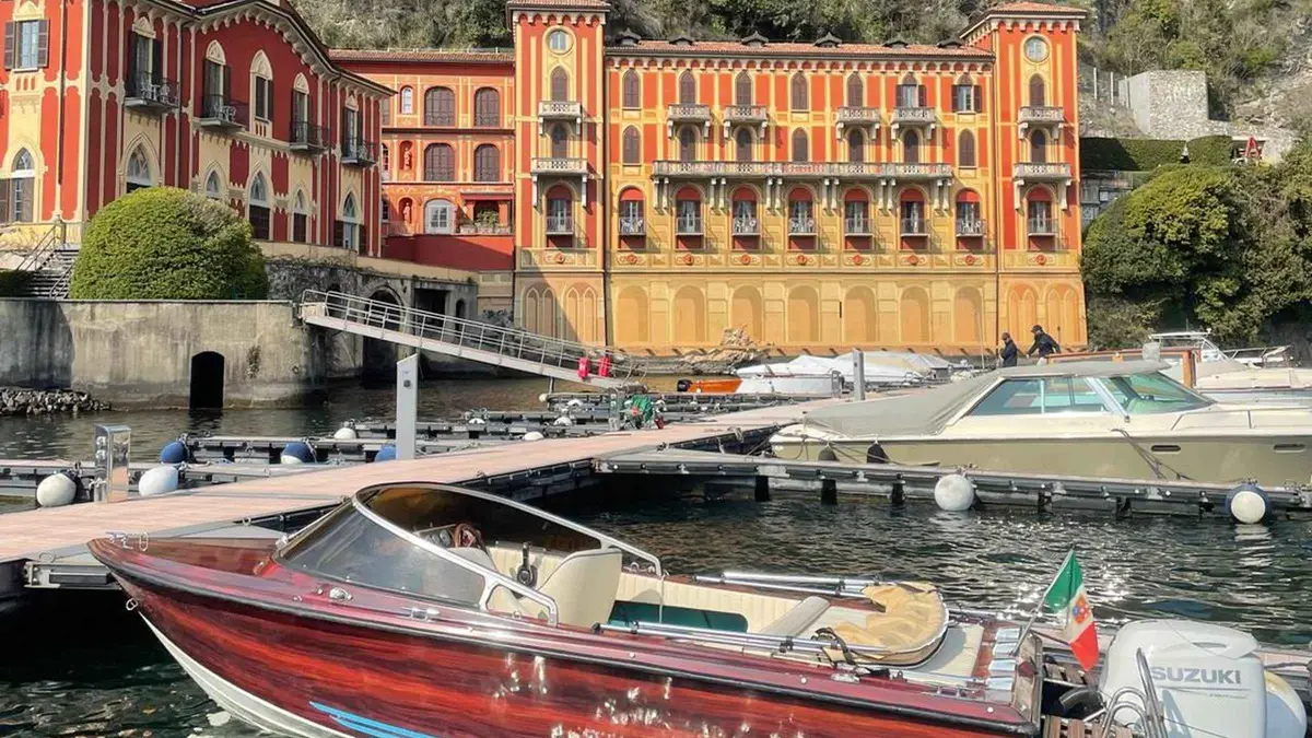 A vintage wooden boat with a canvas sunshade cruising toward Bellagio on a private Lake Como boat tour in Como, Italy