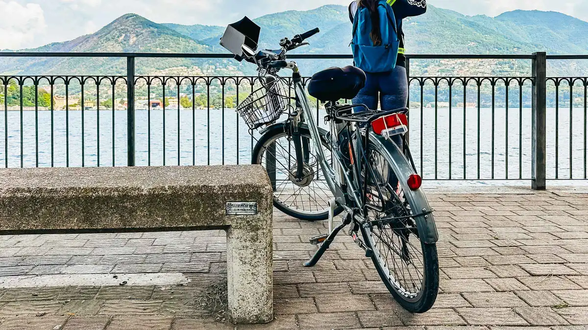 A cyclist with an e-bike and helmet riding the Lake Como shoreline on an e-bike tour in Como, Italy